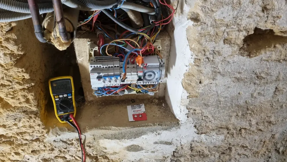 Contrôle d’un ancien tableau électrique avec un multimètre sur un chantier CM’Elec